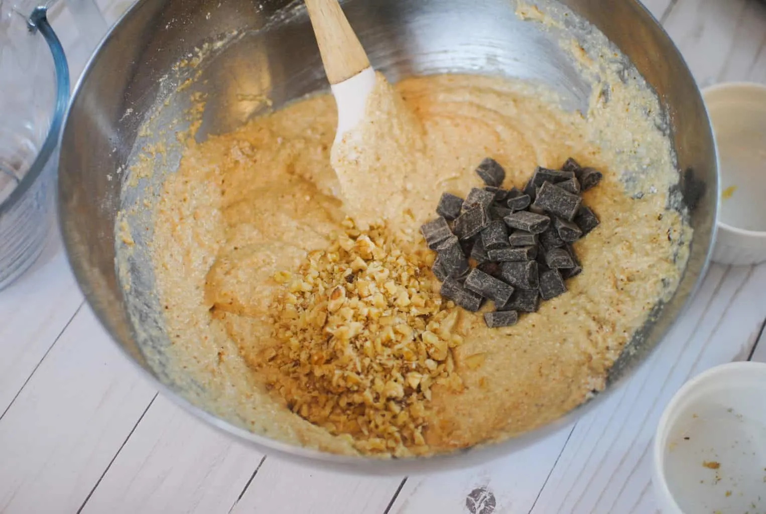 a mixing bowl with batter, nuts, and chocolate chunks