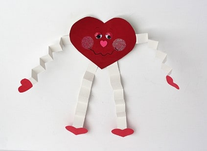A heart cut out of paper with folded paper arms and legs