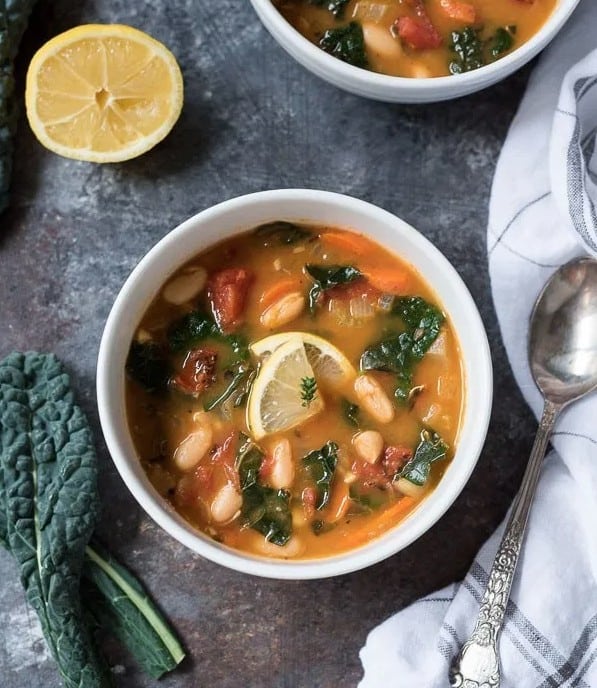 detox recipes - a bowl of white bean and kale soup surrounded by kale and lemon