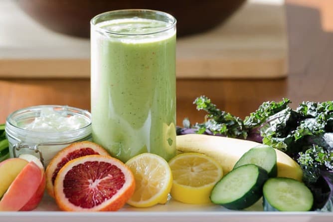 detox recipes - a glass of glowing goddess green detox smoothies surrounded by citrus fruits on a plate