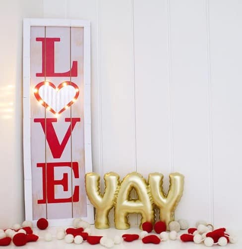 DIY Love Marquee Sign displayed on a Valentines Day table with white and red hearts