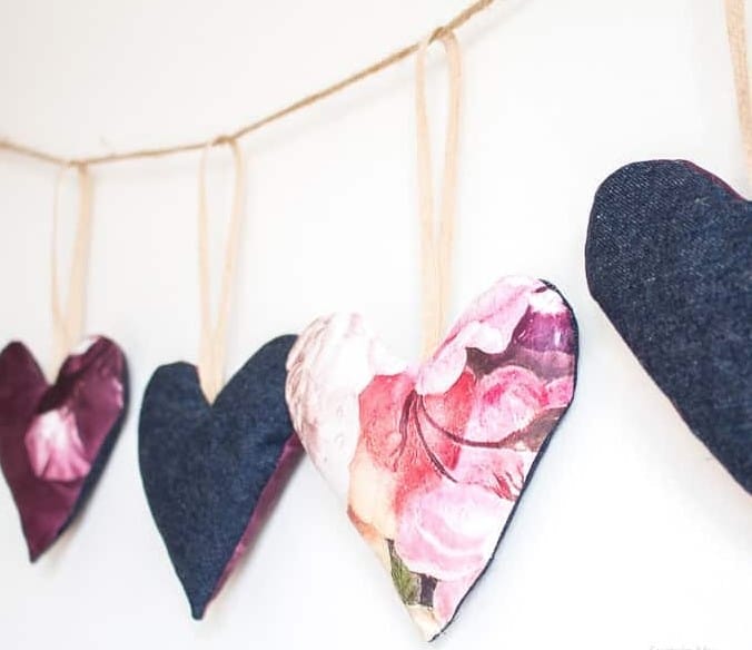 Fabric Scrap Heart Garland: A sweet and whimsical Valentines day decoration. Photo shows four hearts hanging from a piece of twine against a wall. 