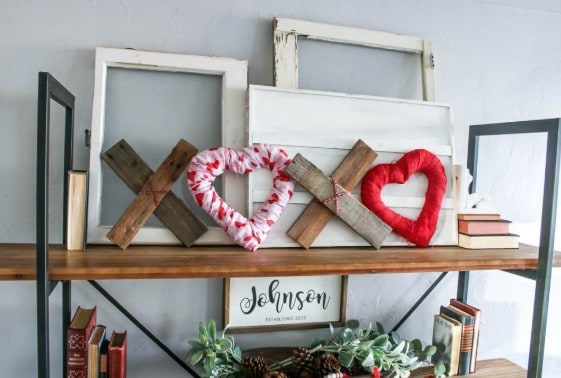 Add a touch of rustic wood scraps and a pop of red fabric for an easy valentines day decor project. Here it is displayed on a bookshelf in front of some other wall decor. 