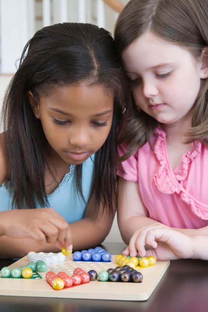 Gameschooling can be a great alternative when you're homeschooling without curriculum. Lots of games are just as educational as they are fun. In this picture, two young girls play Chinese Checkers. 