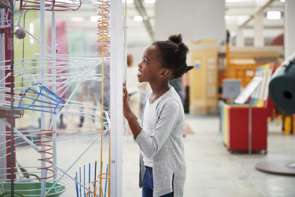 Visiting museums and science centers can be a great way to homeschool without curriculum. In this picture, a young girl checks out a science exhibit.