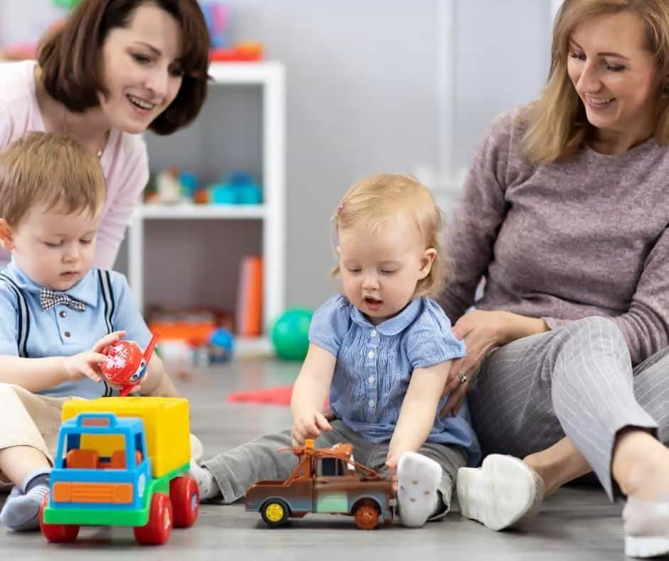 Two moms play with their toddlers on the floor. 