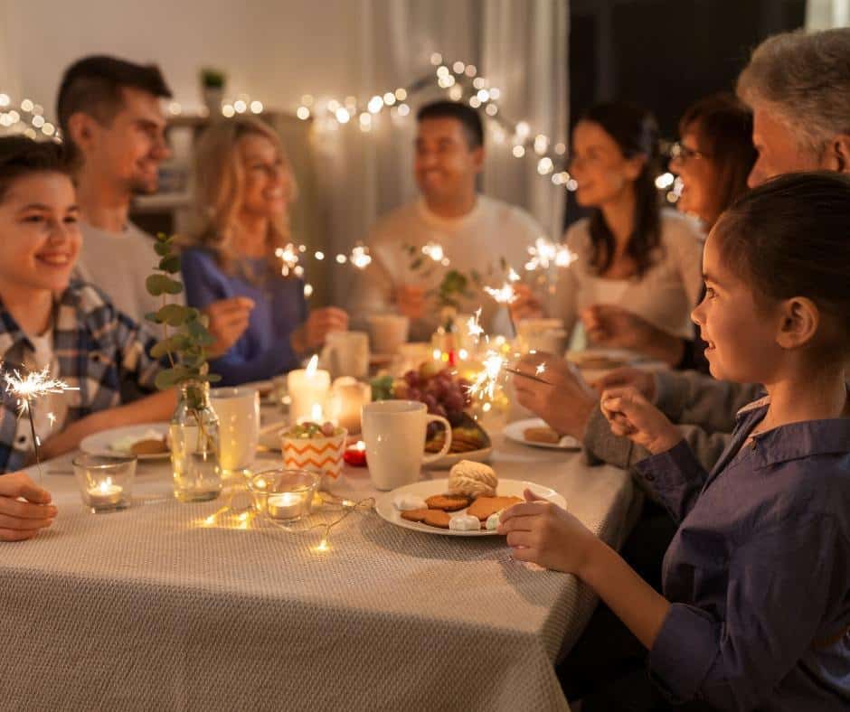 A large gathering of adults and children sit around a table. Hospitality matters because it allows us to demonstrate to our kids the importance of sharing our lives with others. 