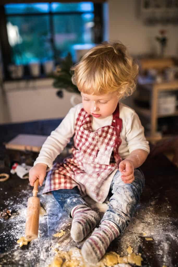 Toddler boy making gingerbread cookies at home.
