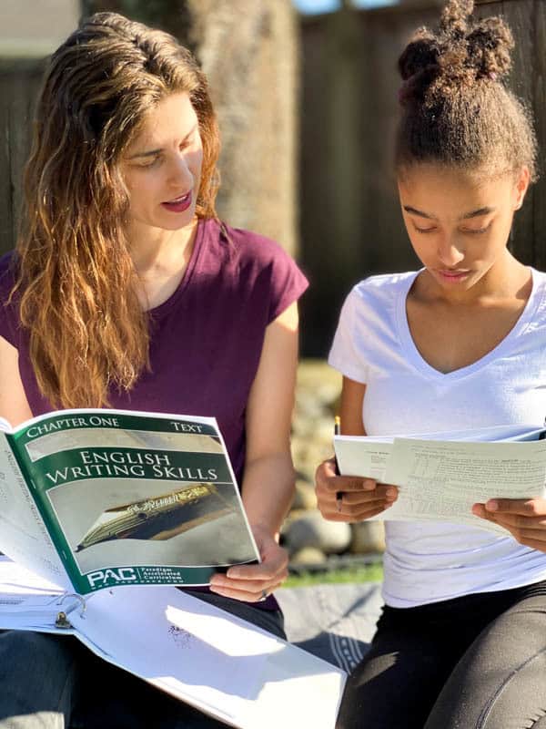 A mom and a daughter study high school english curriculum books together outside