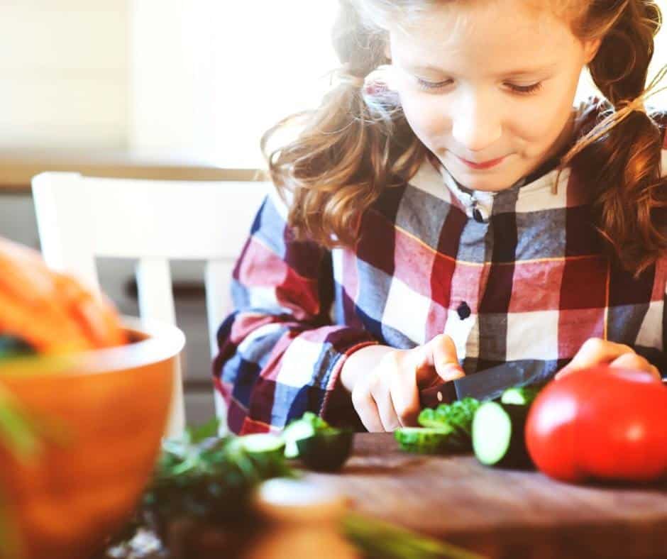 A little girl chops vegetables for a salad. Cooking with your kids is a great activity to do when you're taking a day to unplug from technology.