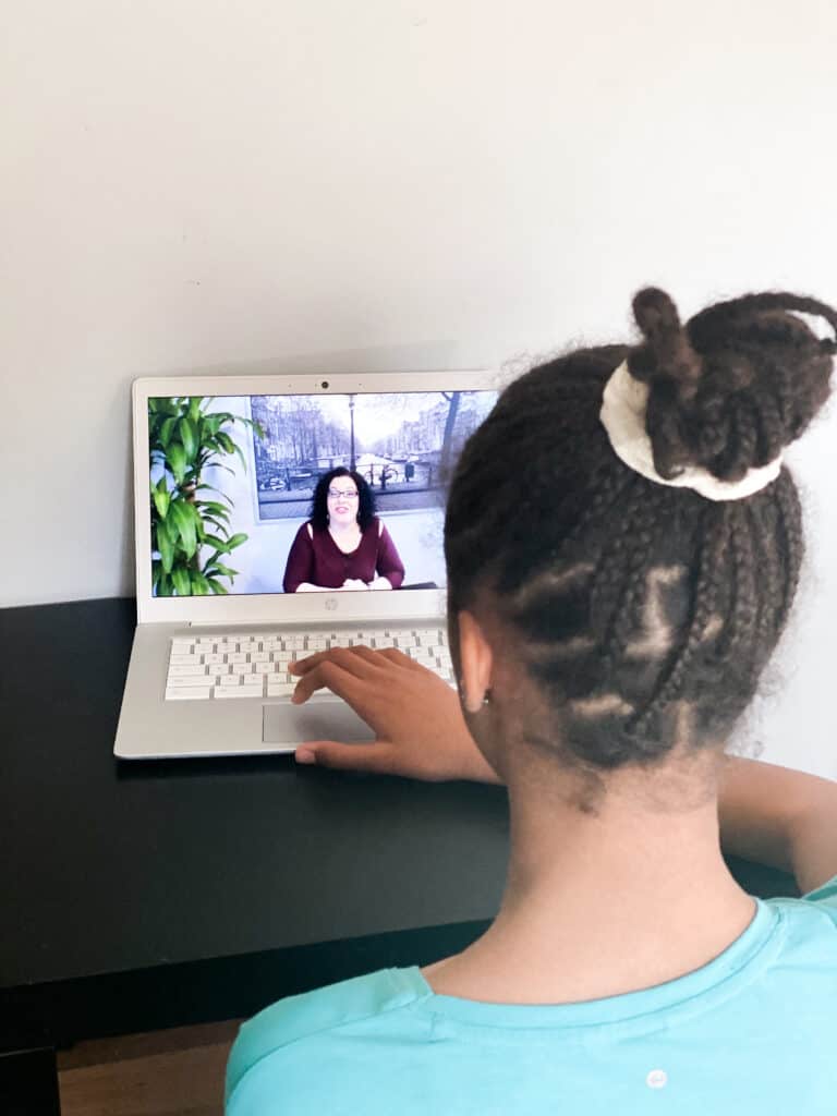 A girl sits at a desk watching a video from the Advanced writing class for homeshool high school students on the Mr. D Math website