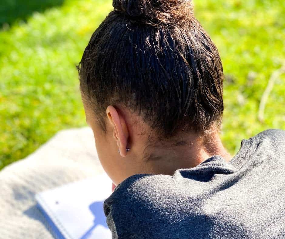 A girl writing in a notebook outside.