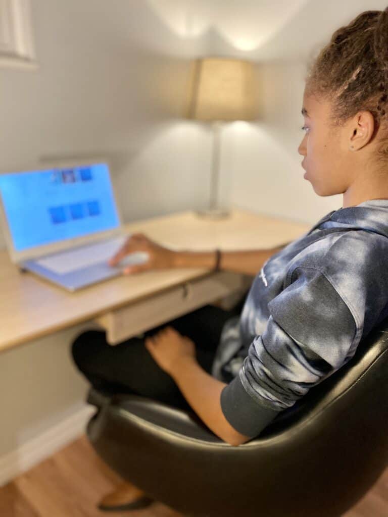 a middle school child works on an online writing course on a laptop