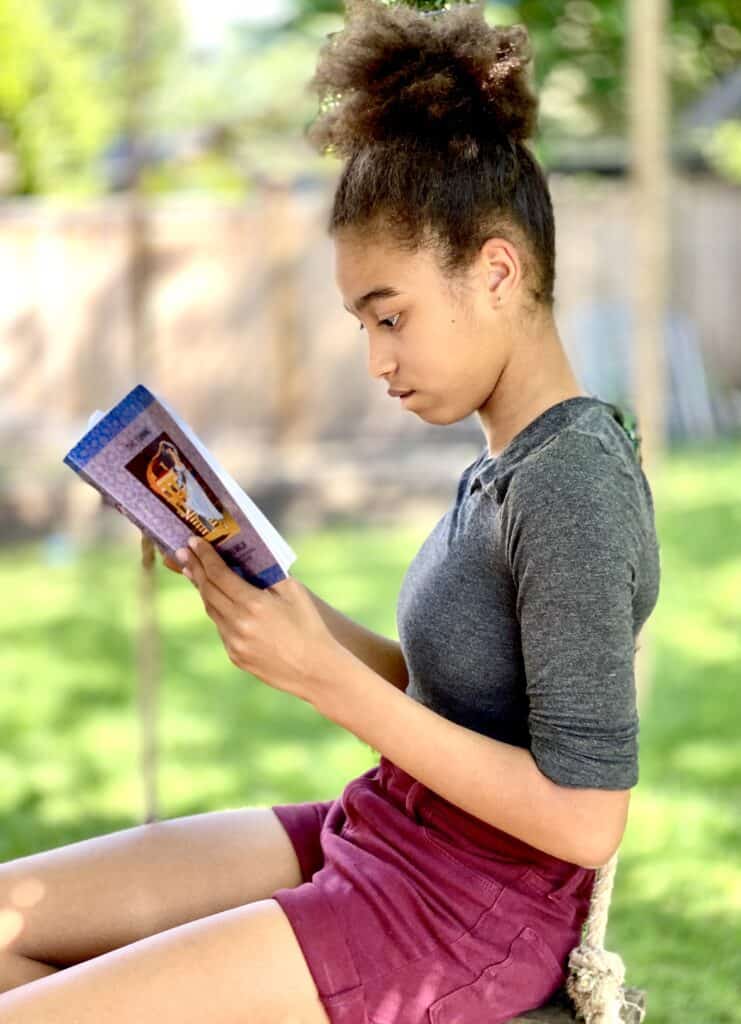 a girls reads outside - choosing a literature-based program that kids love can improve the family dynamic in your homeschool