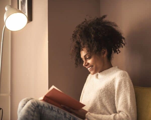 woman comfortably reading a book in a corner