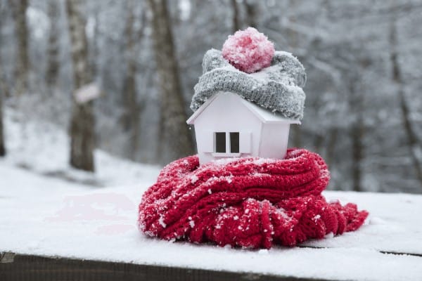 a house snuggled up inside a scarf and a hat - there are many cheap ways to heat up a house in winter