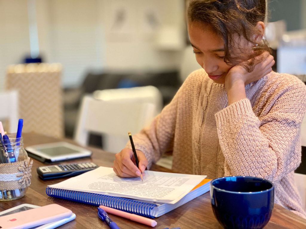 Mr D Math Review - a girl sits at a table and works on a math assignment