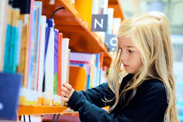 a little girl looks through books at a library. The library is a great resource for homeschool families and we spent much of our kindergarten year hanging out there. 