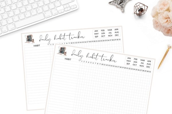 Flatlay image with two printable habit tracker, laptop and desk supplies