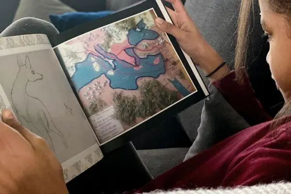 a girl looking through a photobook of her art