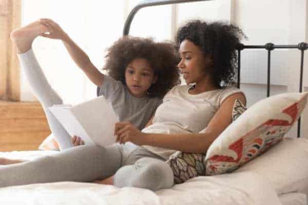 a mom and a child read in a bed