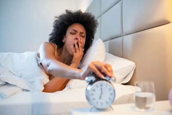 a woman turns off her alarm clock