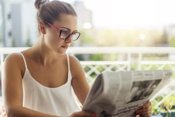 a woman reads a newspaper instead of using her phone