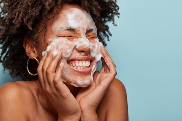 a woman washes her face as part of a morning skin care routine