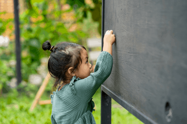 little girl drawing on a backyard chalkboard