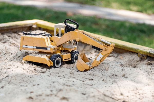 a toy excavator in a sandbox - a sandbox is a classic DIY backyard idea that you can pull together on a budget