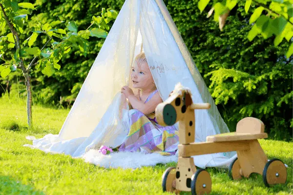 a little girl plays in a DIY backyard teepee