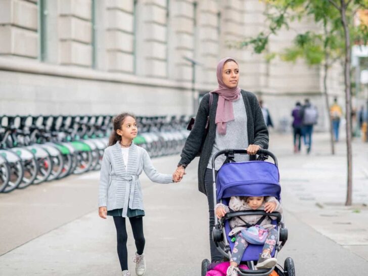 walking with kids | a mother walks with her daughter and pushes a stroller