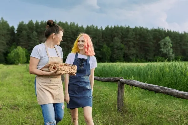 a mother and teen connect while picking strawberries