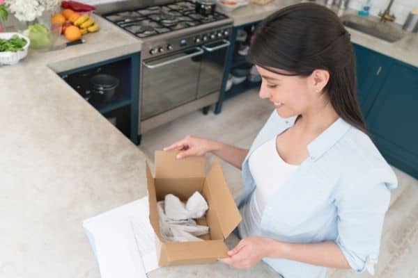 gifts that keep giving | if you know someone who shops on Amazon a lot, a subscription to Amazon Prime could come in really ahndy | a woman opens a box in her kitchen
