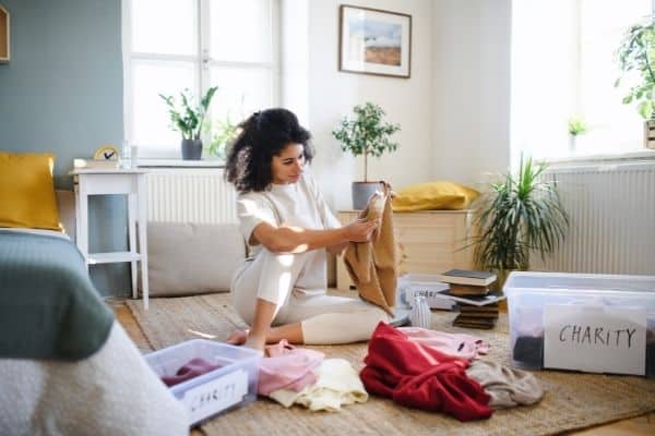 how to start organizing a messy house | a woman sorts through clothes in her bedroom