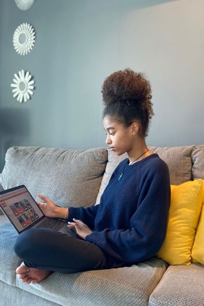 a girl uses a laptop on a couch