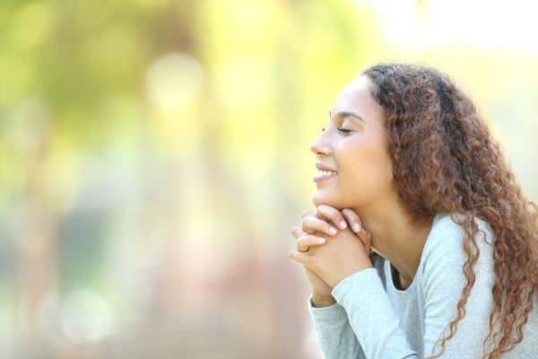 a woman has her eyes closed in the park and rests her chin on her hands