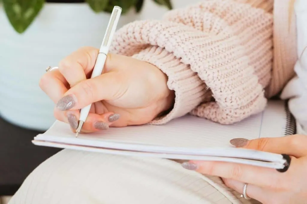 a woman's hand writing in a notebook