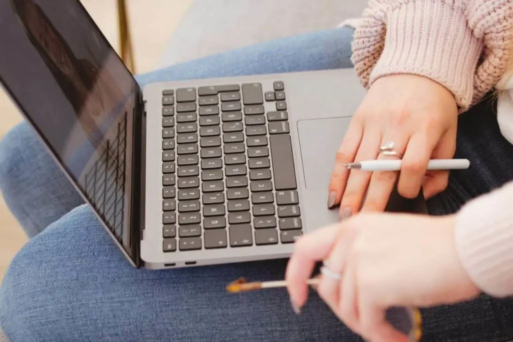 a woman's hands typing on a laptop