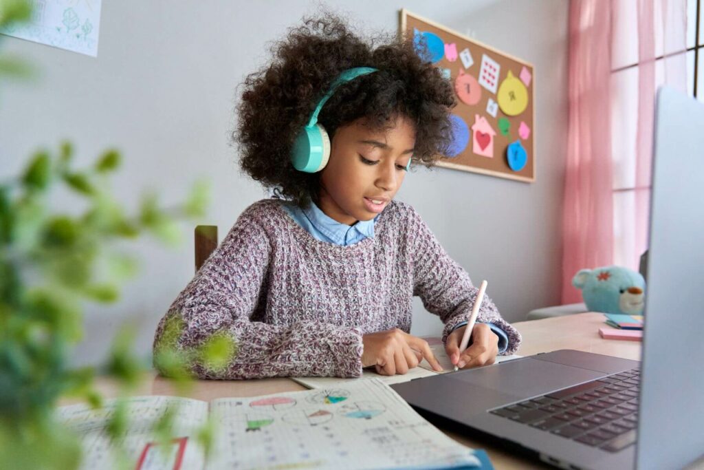 a kid works at a laptop and listens to headphones