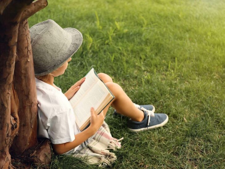 a boy reads outside under a tree