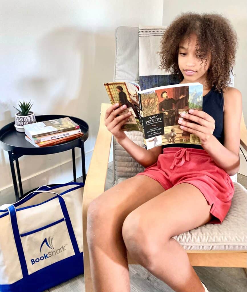 girl sits in a chair and reads a poetry book