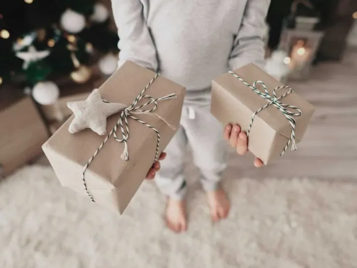 a young girl holds two gifts wrapped in brown paper