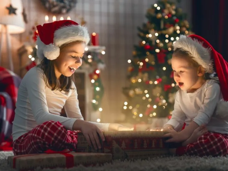 a girl opens a present with her sister