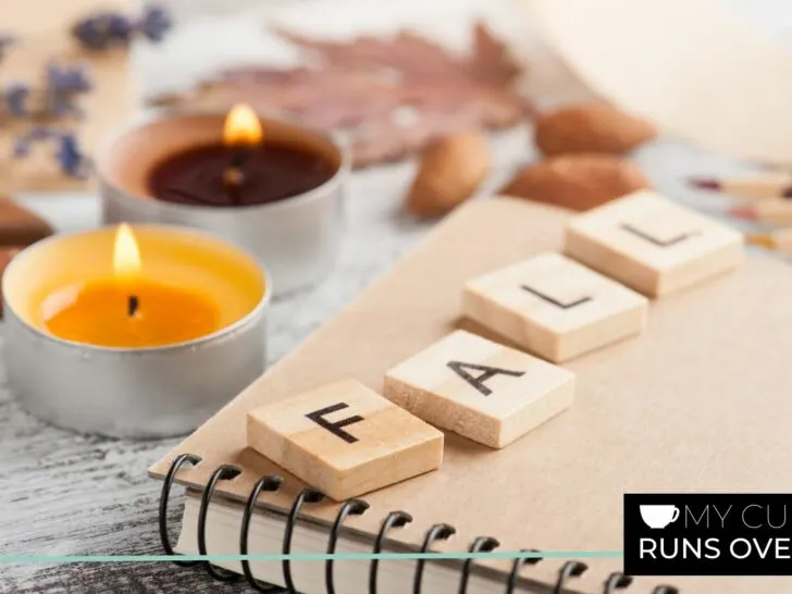 a notebook with Scrabble tiles that spell fall and some candles and leaves